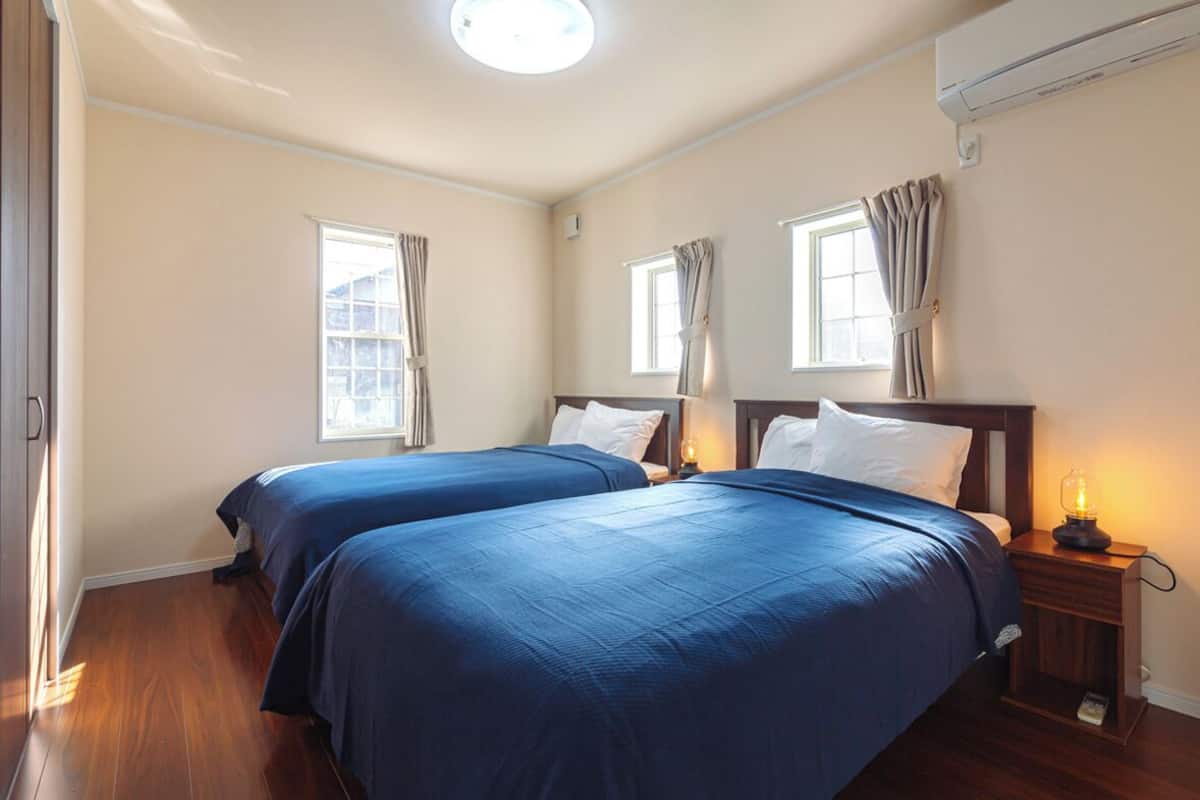 A hotel room with two beds, a nightstand with a lamp, and an air conditioning unit.