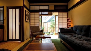 Un interno tradizionale giapponese con pavimento in tatami, un tavolino, un divano e porte scorrevoli.