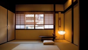 Una tradizionale stanza giapponese con pavimento in tatami, una finestra con paravento shoji, un tavolino e una lampada da terra.