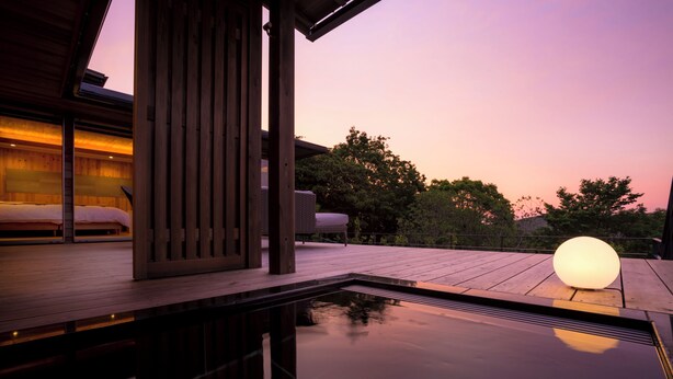 Una terraza de madera con piscina, una cama y una lámpara esférica grande.