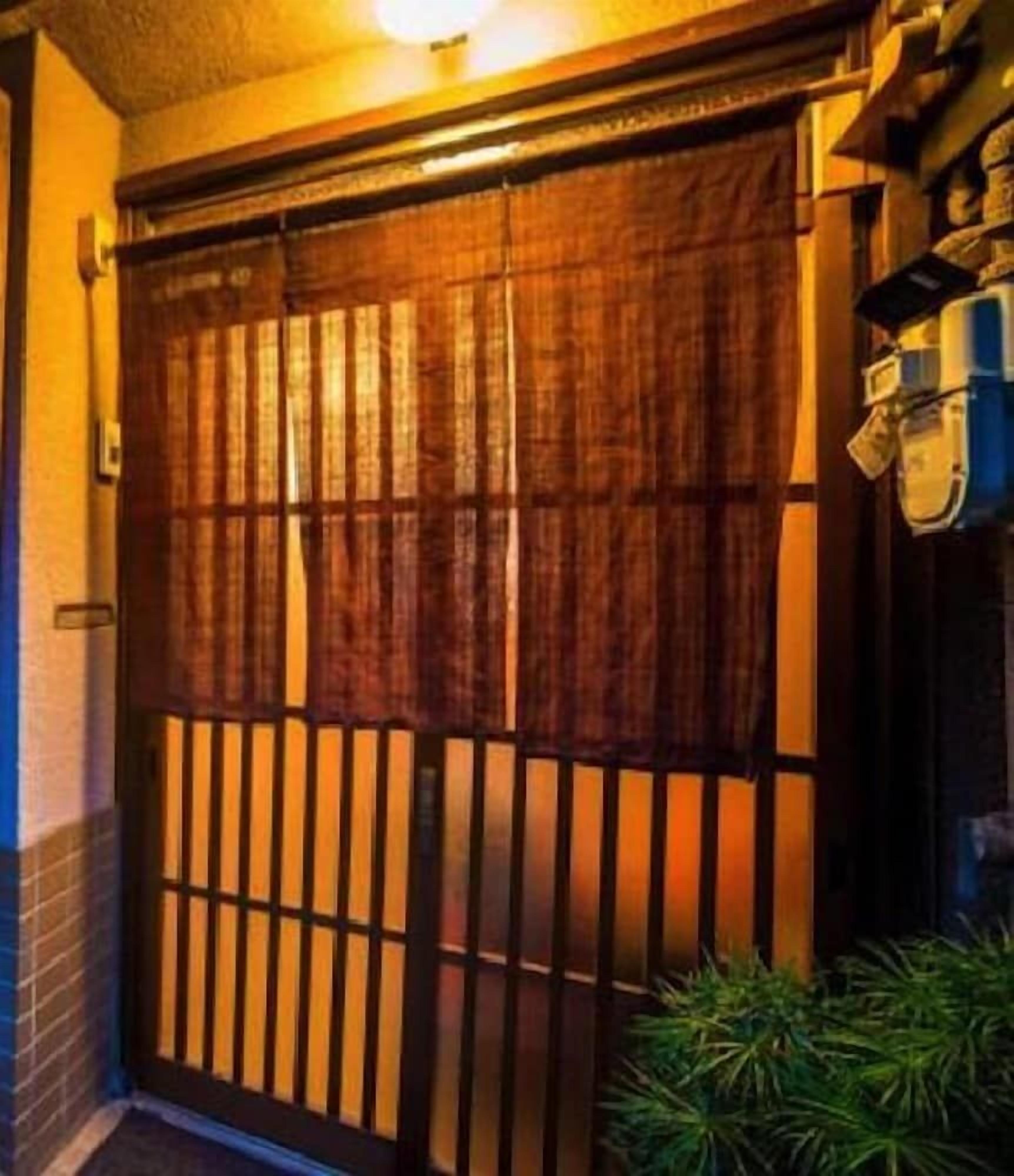 A wooden gate with vertical slats, a brick wall, and a small plant in the foreground.