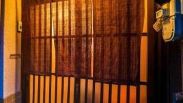 A wooden gate with vertical slats, a brick wall, and a small plant in the foreground.