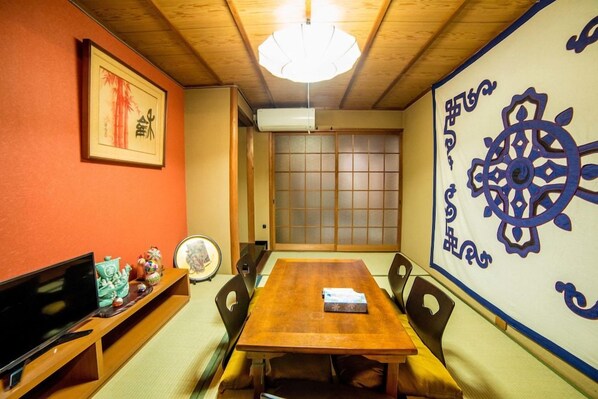 A traditional Japanese room with tatami flooring, a wooden table, a television, and a shoji screen. - Kyoto Kumano House (Kyoto)