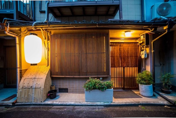 A traditional Japanese entrance with a wooden gate, a sliding door, and a small wooden structure to the left. - Kyoto Kumano House (Kyoto)