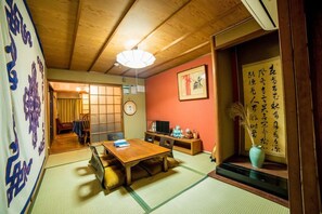 Ett traditionellt japanskt rum med tatamimattor på golvet, ett lågt bord och en tv.