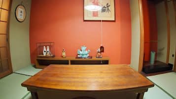 Una habitación tradicional japonesa con suelo de tatami, una mesa de madera y un estante bajo con diversos objetos.