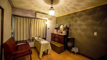Una habitación con un sofá, una mesa con mantel, un armario y una lámpara en el techo.