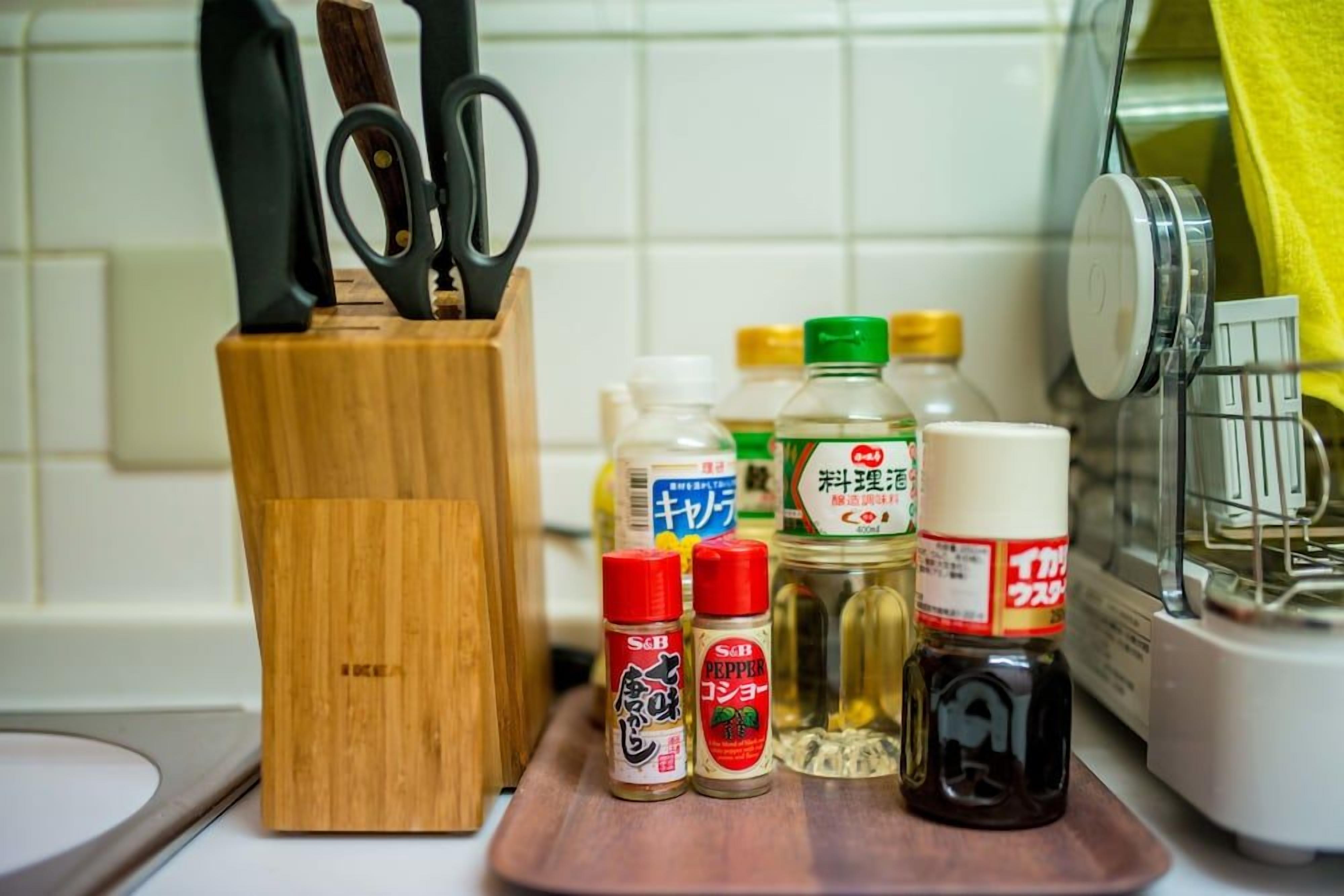 A kitchen counter with various condiments, a wooden knife block, and kitchen utensils.