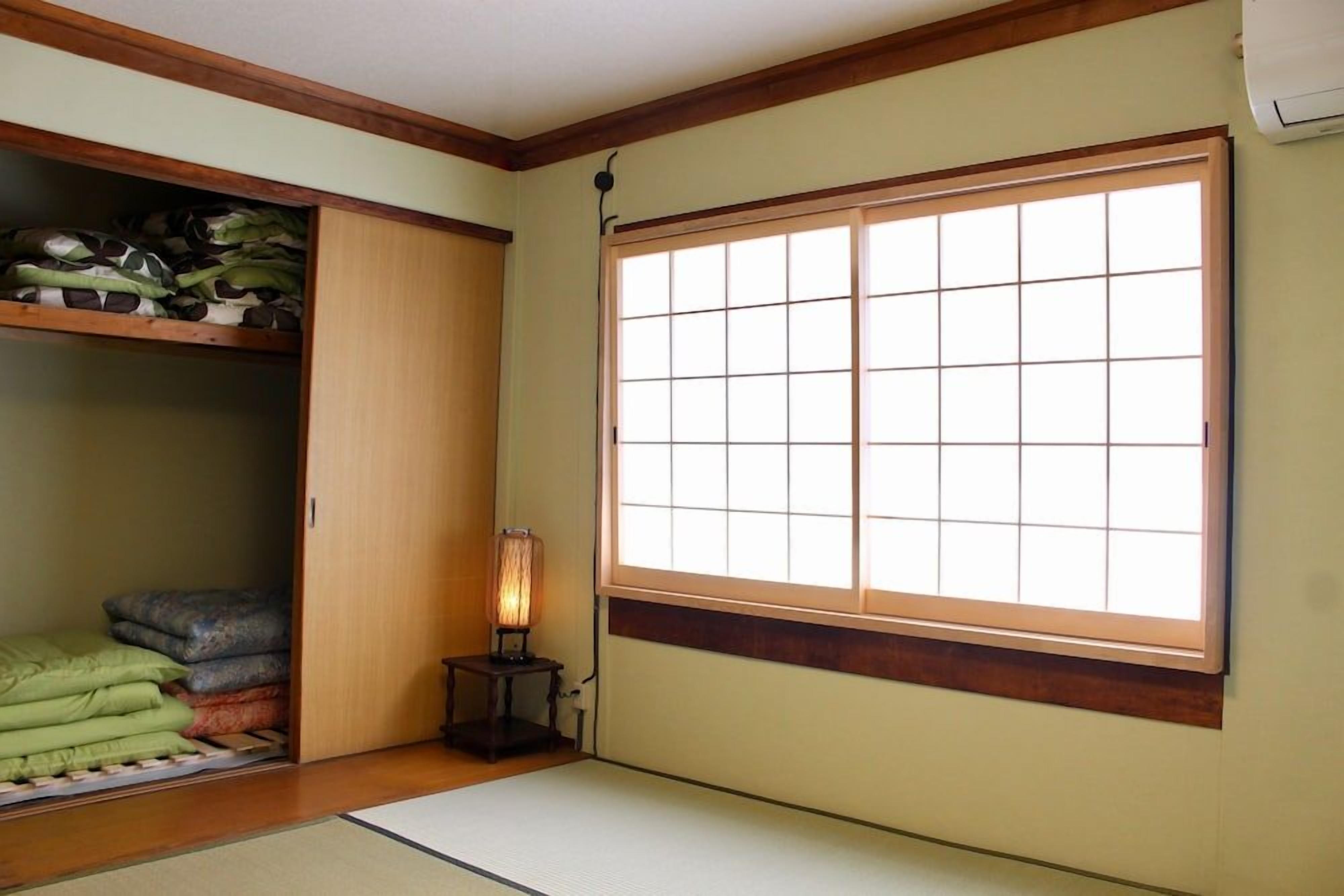 A room with tatami flooring, a sliding door closet, and a large window with a grid pattern.