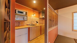 A compact kitchen with a microwave, toaster, and refrigerator, wooden cabinets, and a tiled backsplash. - Yadoya Sen no Sato (Tokyo)