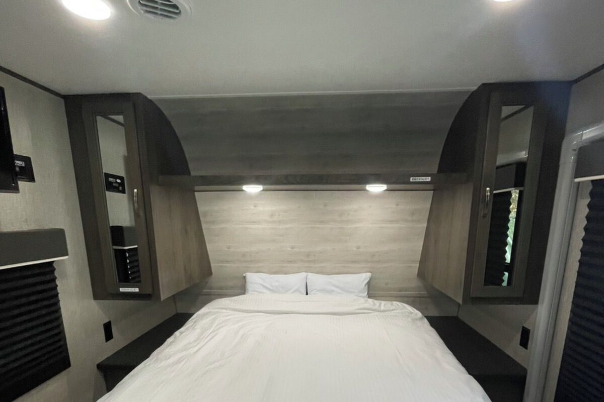 Una habitación de hotel con una cama grande, un cabecero de madera e iluminación integrada.