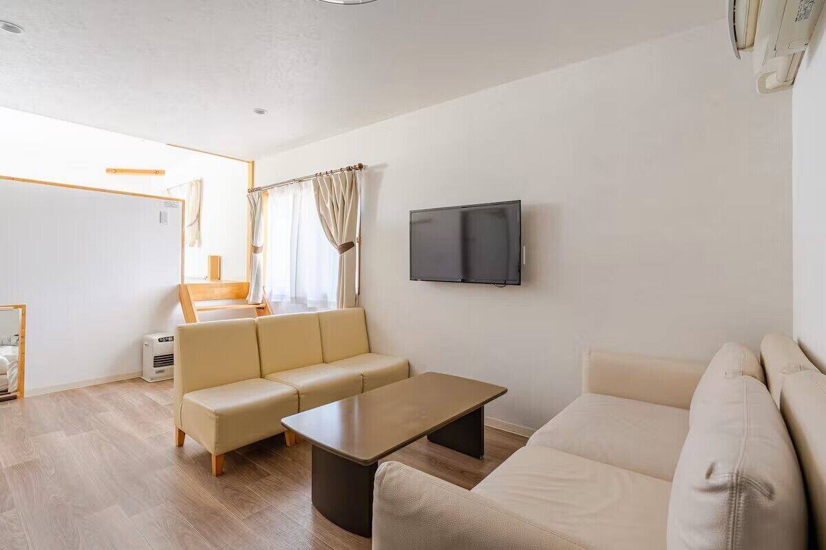 A modern living room with a sofa, a coffee table, and a TV mounted on the wall.