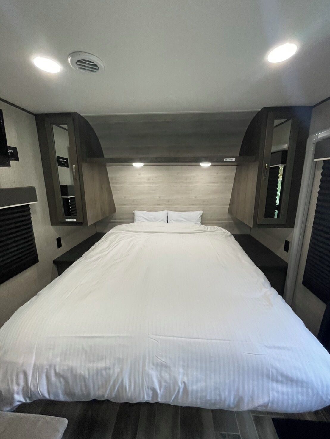 Een hotelkamer met een groot bed, een houten hoofdeinde en ingebouwde verlichting.
