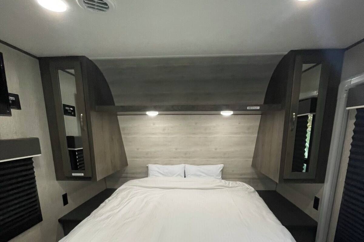 A hotel room with a large bed, a wooden headboard, and built-in lighting.