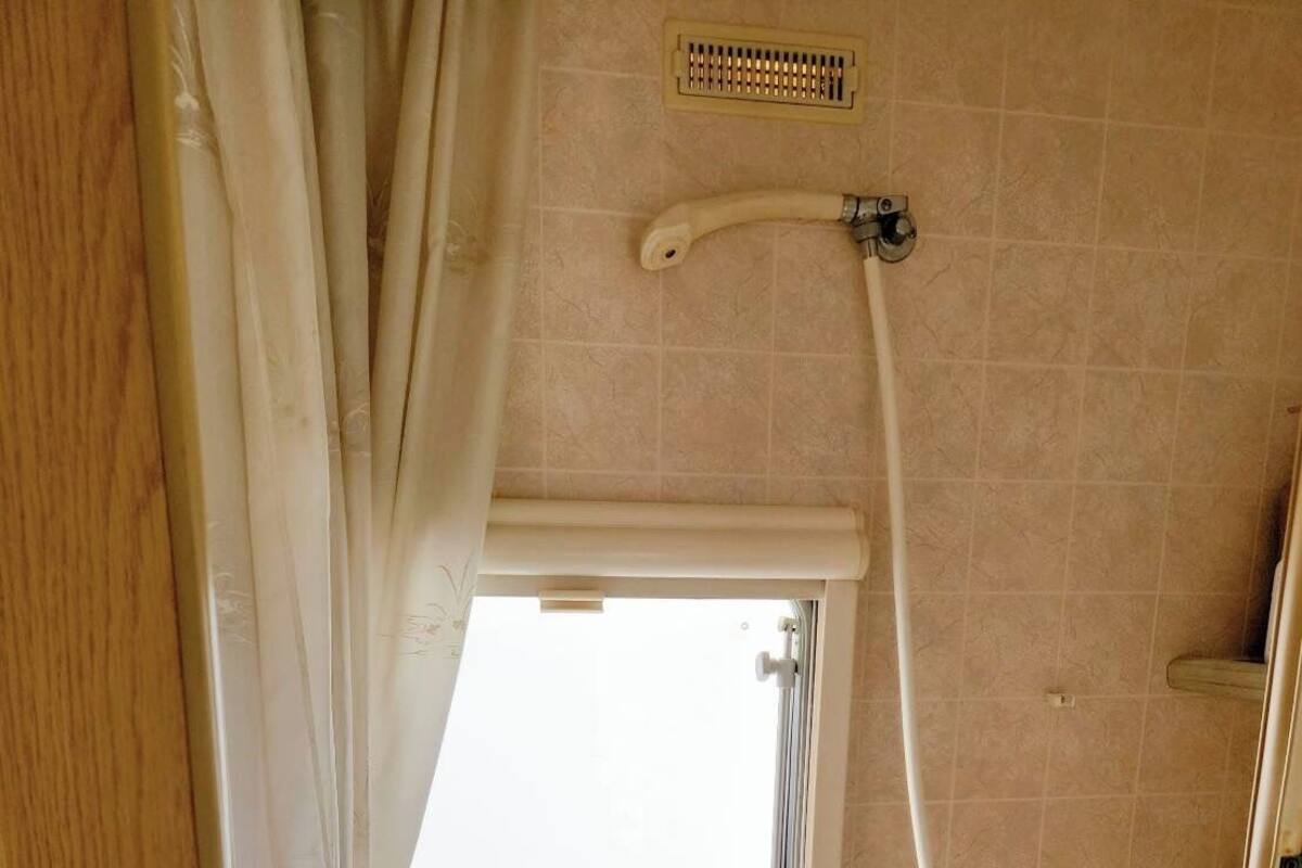 A compact bathroom with a window, shower, and toilet.