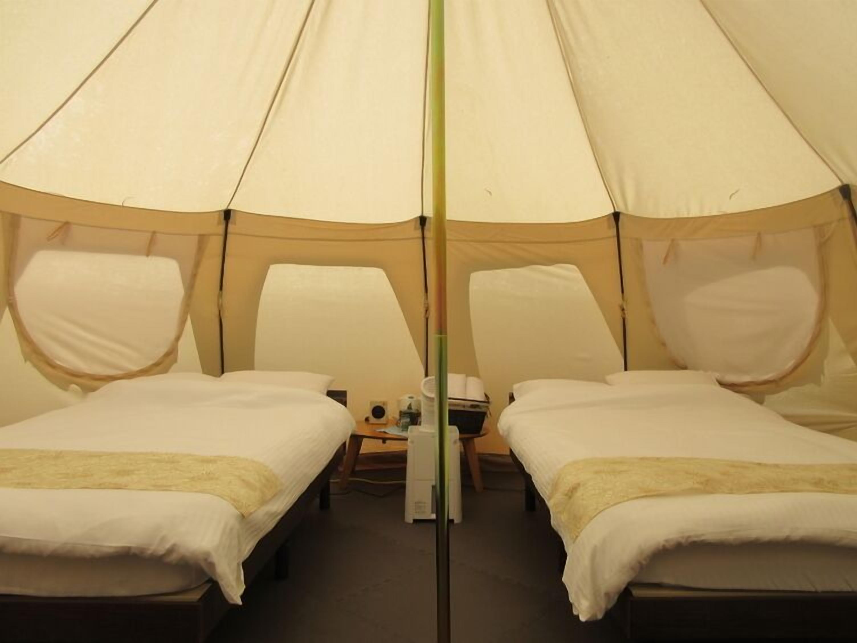 Een tent met twee bedden, een tafel en een stoel.