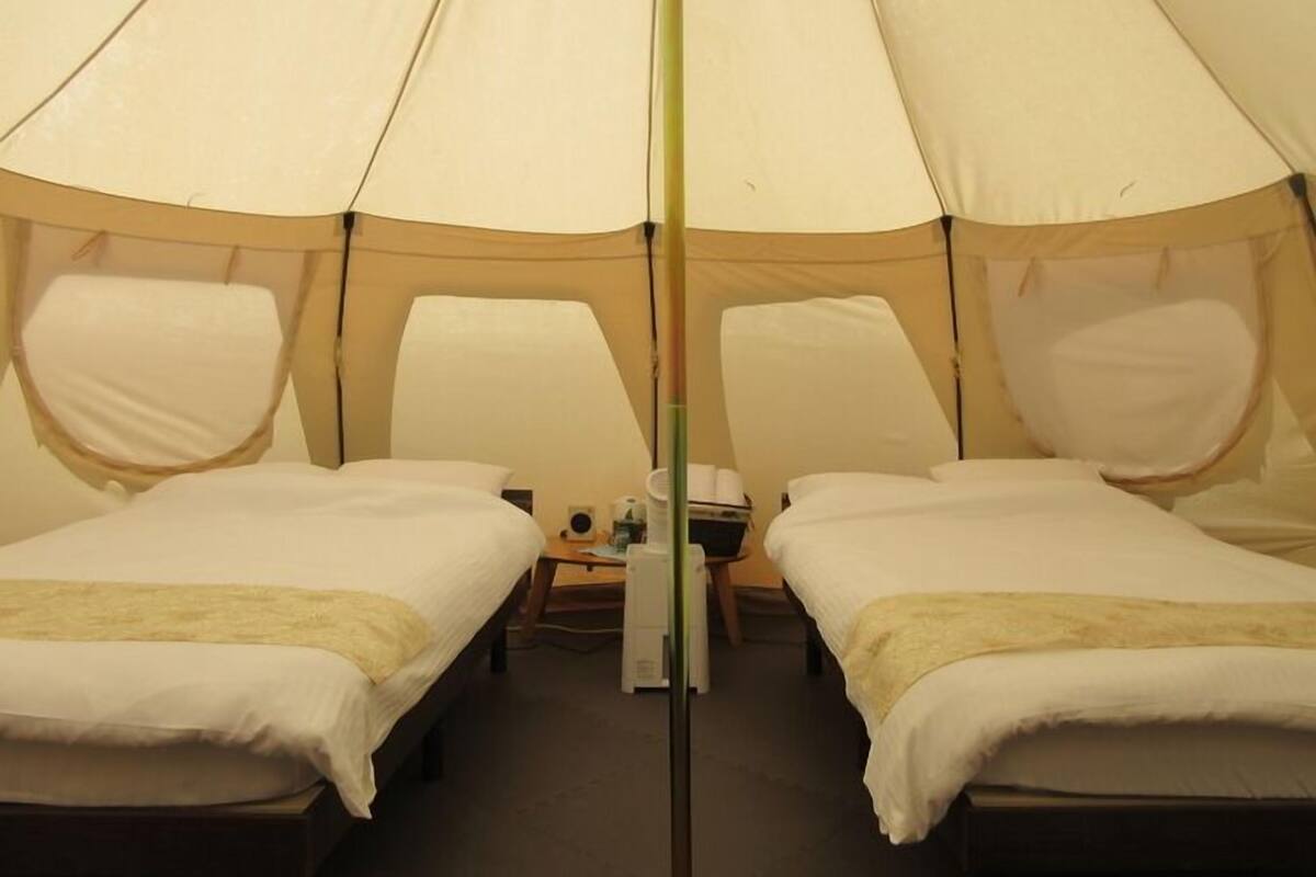 A tent with two beds, a table, and a chair.