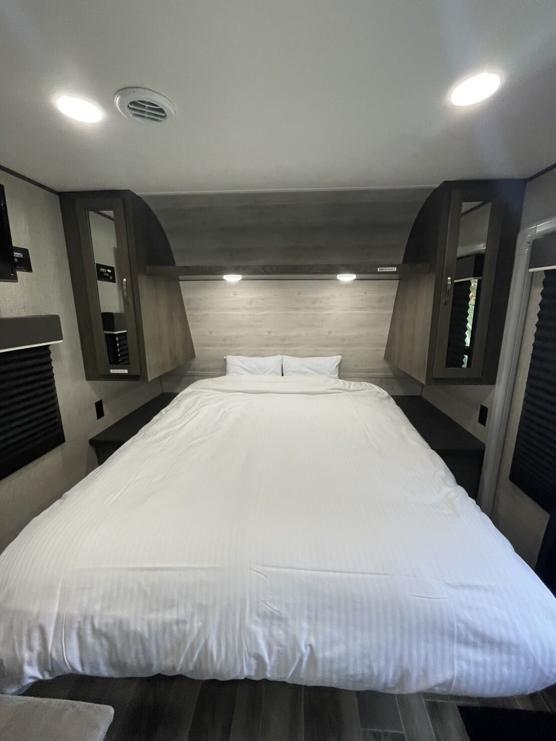 Ein Schlafzimmer mit einem großen Bett, eingelassenen Deckenleuchten und einem Holzkopfende.