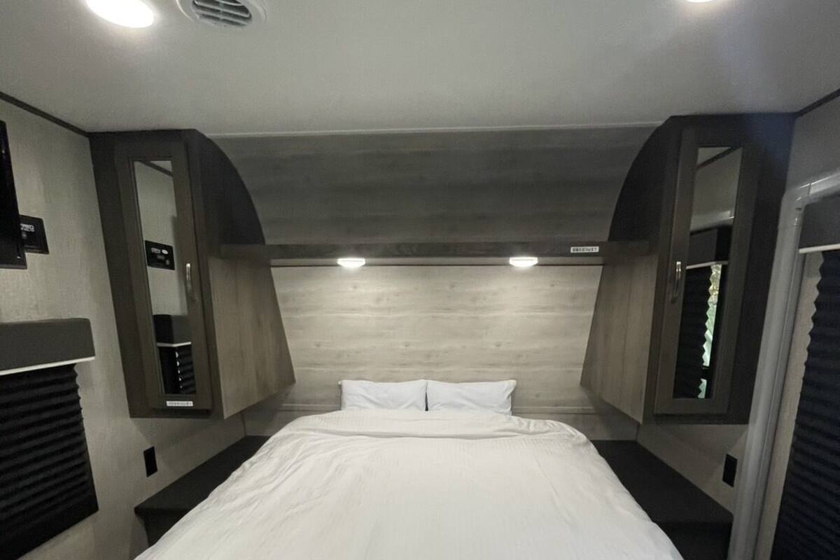 A bedroom with a large bed, recessed ceiling lights, and a wooden headboard.