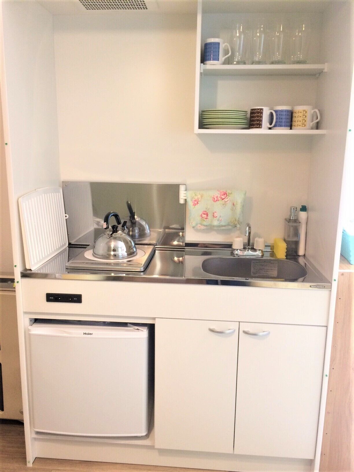 Een kleine keuken met een koelkast, fornuis, spoelbak en een keukenkastje.