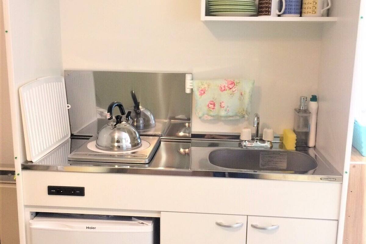A compact kitchen with a refrigerator, stove, sink, and a small cabinet.