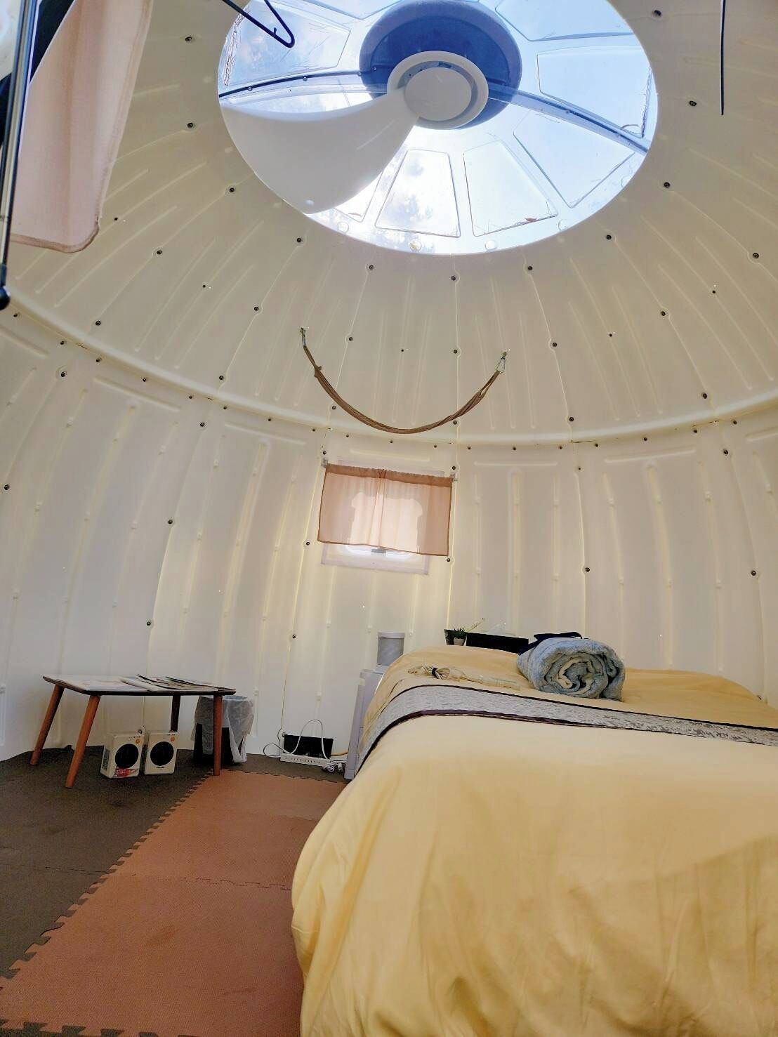 Een kamer met een bed, een tafel en een plafondventilator.