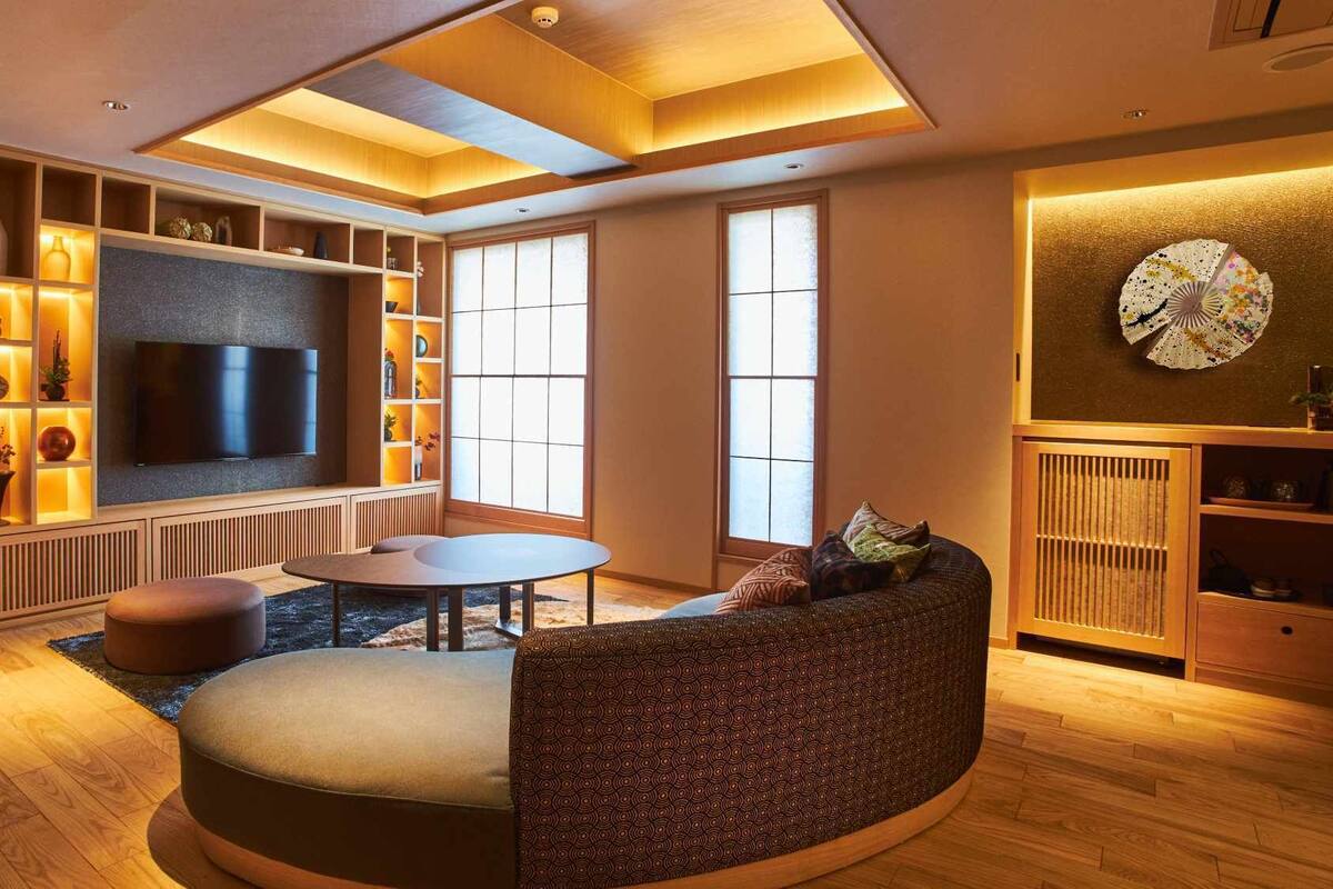 A modern living room with a TV, seating, and a large window.