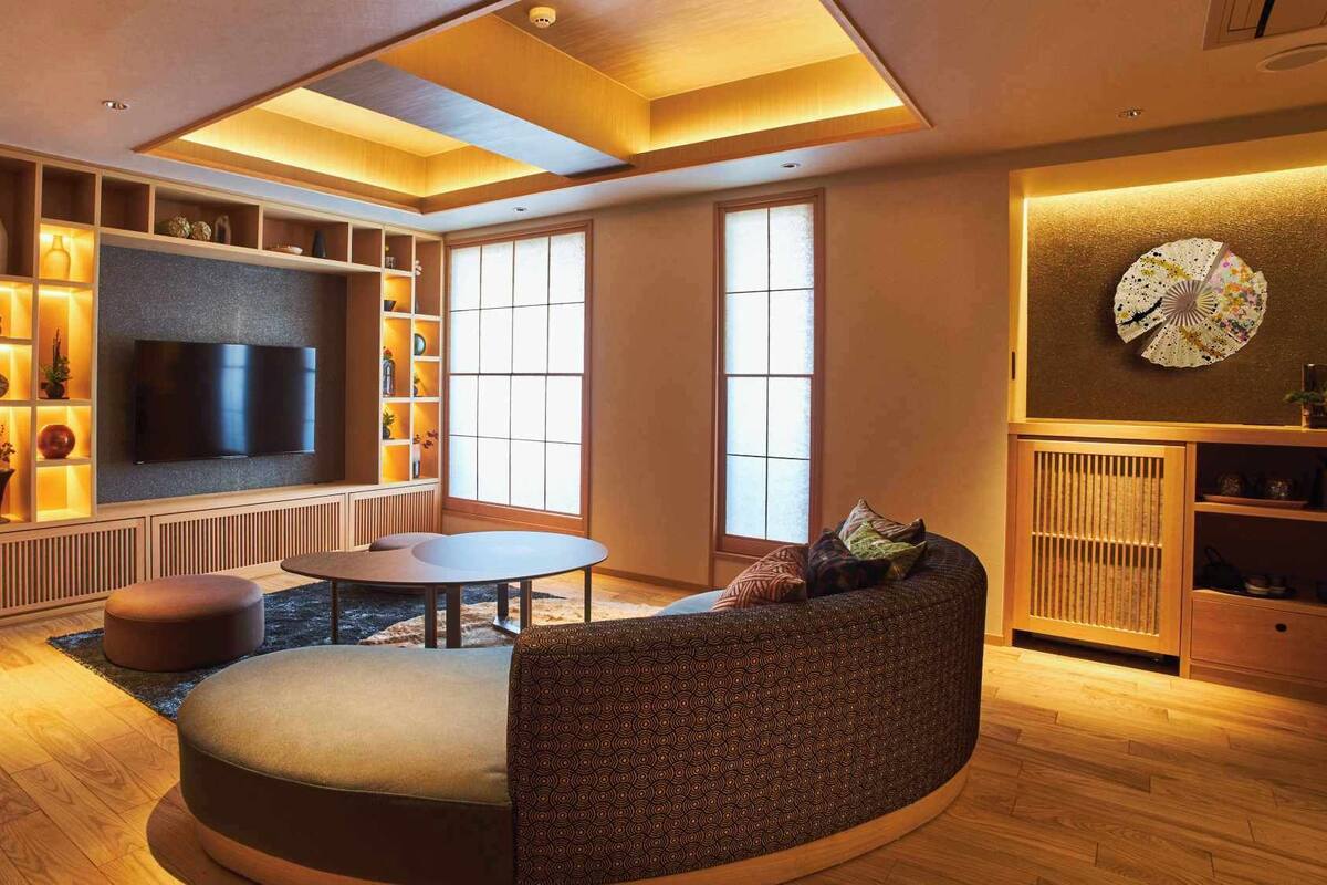 A modern living room with a TV, seating, and a large window.
