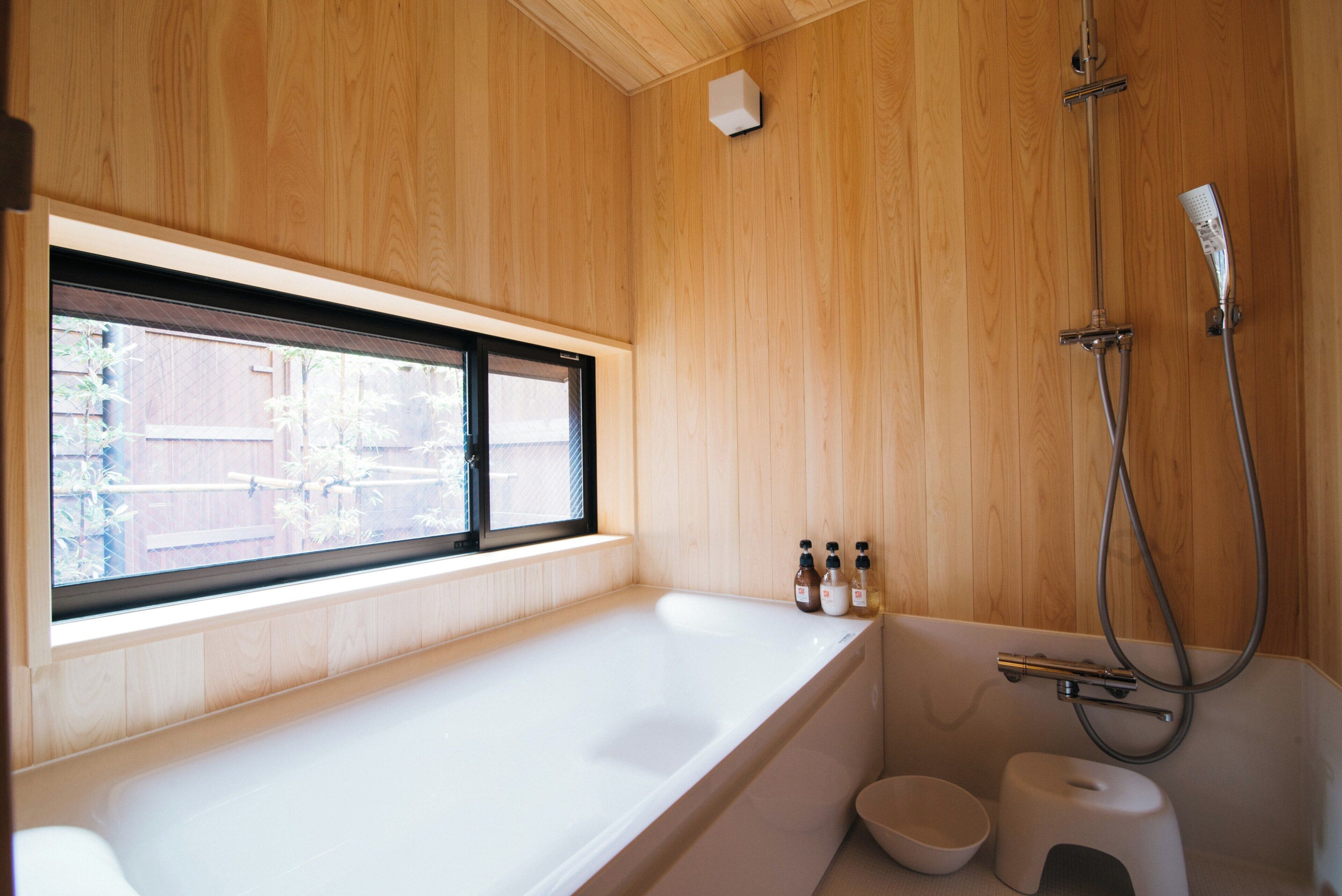 A modern bathroom with a large bathtub, a window, and a shower.