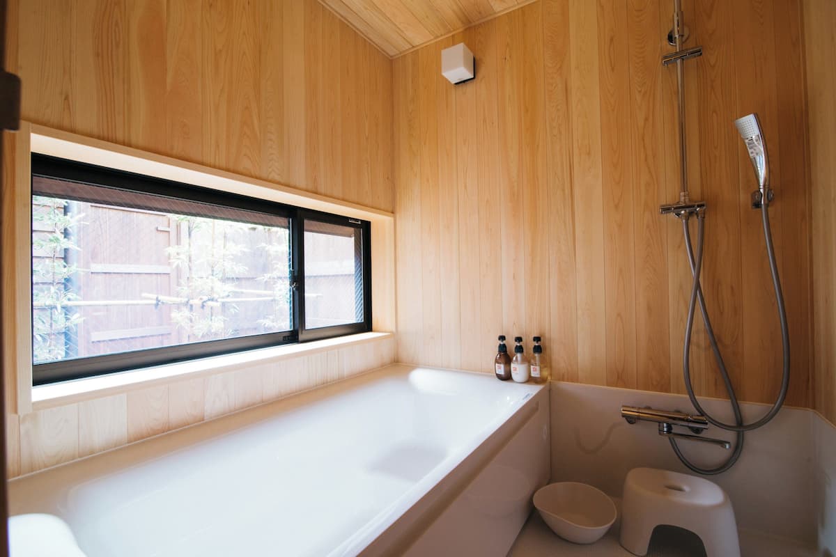 A modern bathroom with a large bathtub, a window, and a shower.