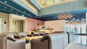 A modern lobby with leather seating, a reception desk, and a glass entrance.