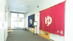 A hallway with a carpeted floor, a bench, and two flags on stands.