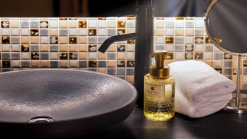 A bathroom sink with a black basin, a soap dispenser, and a folded white towel.