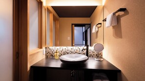 Un baño con un lavabo redondo, un espejo y un salpicadero de azulejos.