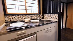 A kitchen with a black countertop, a sink, and a window with a grid pattern. - Rinn Gojo Mibugawa East (Kyoto)