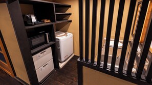 Una kitchenette compacta con microondas, un refrigerador pequeño y un lavamanos.