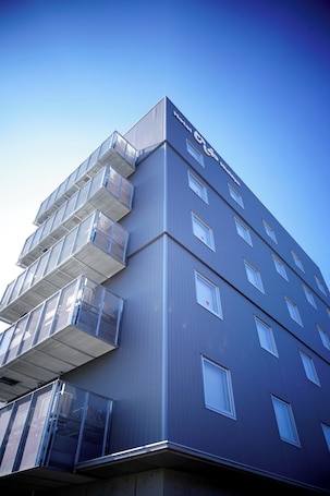 A modern building with a flat roof, multiple balconies, and a clear sky.