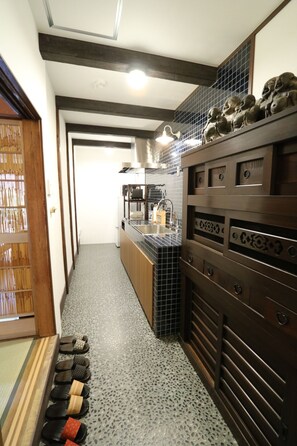 A narrow kitchen with a tiled backsplash, a built-in oven, and a countertop with a sink. - Satsukian (Kyoto)