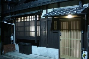 A traditional Japanese building with a wooden door, a sliding gate, and a small trash bin outside. - Satsukian (Kyoto)