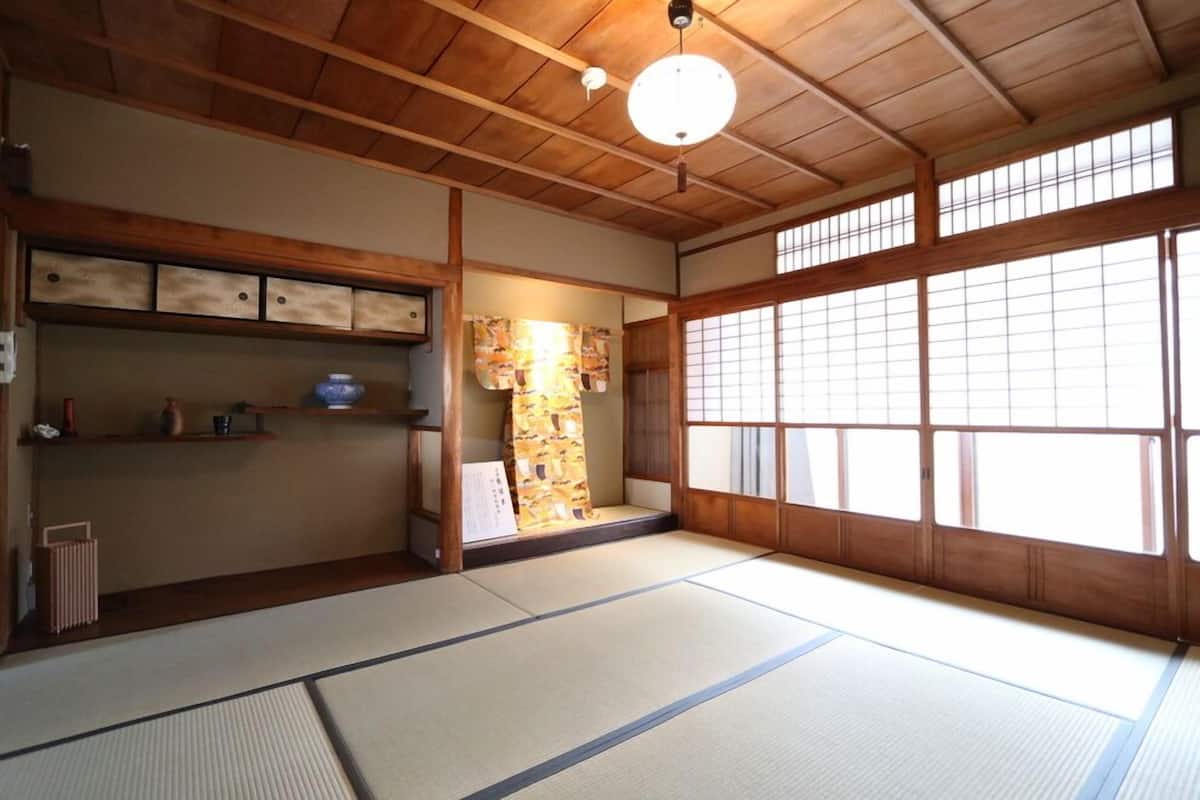 Una habitación japonesa tradicional con suelo de tatami, vigas de madera y puertas correderas.