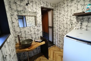 A bathroom with a wooden sink, a mirror, and a white toilet. - Satsukian (Kyoto)