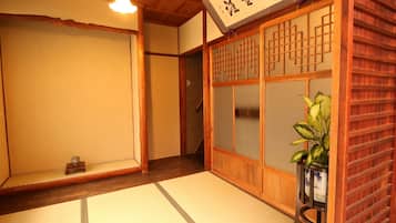 A traditional Japanese room with tatami flooring, a shoji screen, and a wooden staircase.