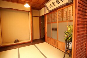 A traditional Japanese room with tatami flooring, a shoji screen, and a wooden staircase. - Satsukian (Kyoto)
