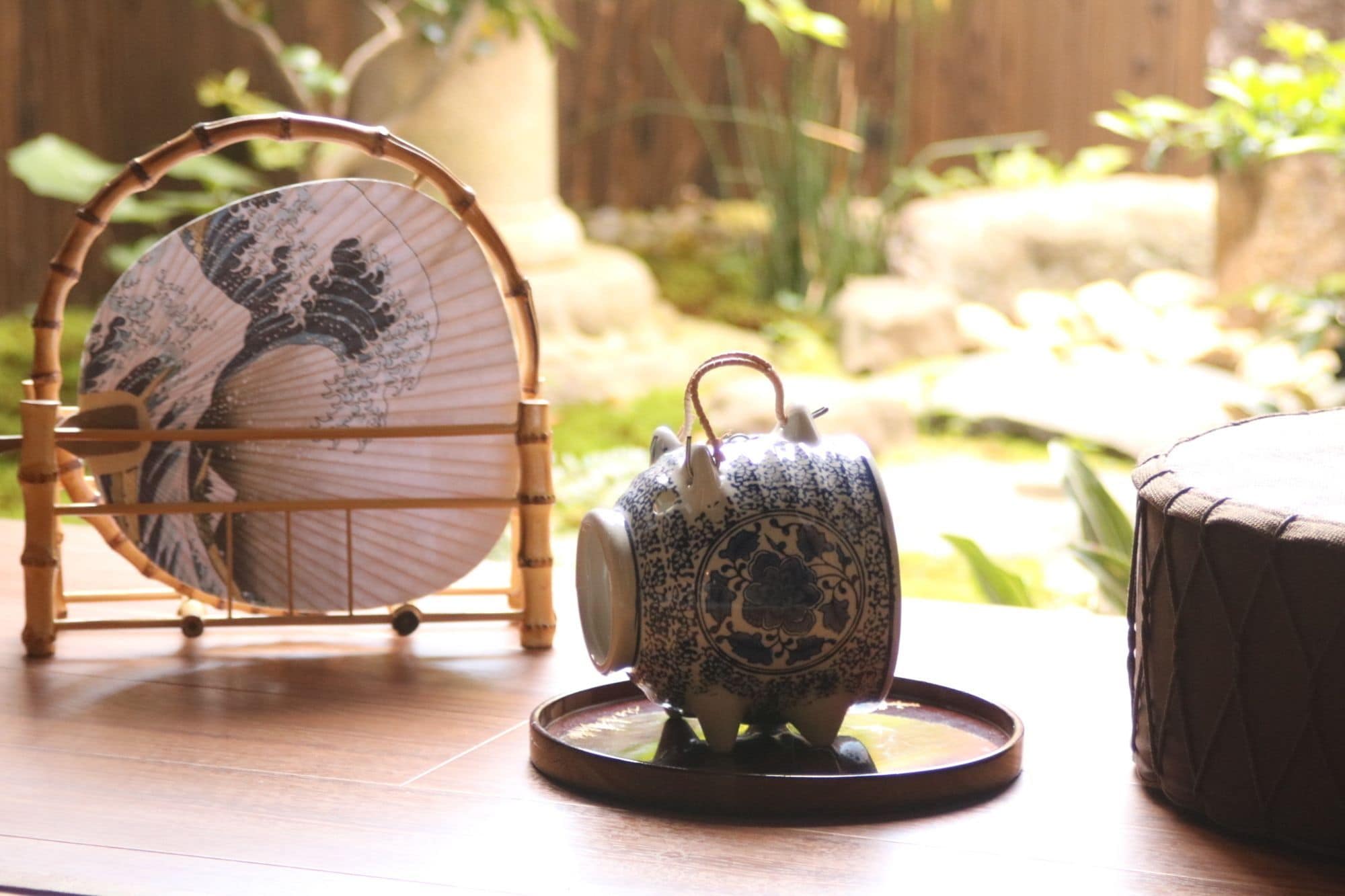 A tea set on a tray, a decorative plate on a stand, and a wooden stool.