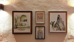 Tres obras de arte enmarcadas sobre una pared texturizada, iluminadas por luces empotradas.