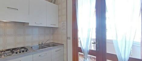 A kitchen with white cabinets, a gas stove, and a sink.