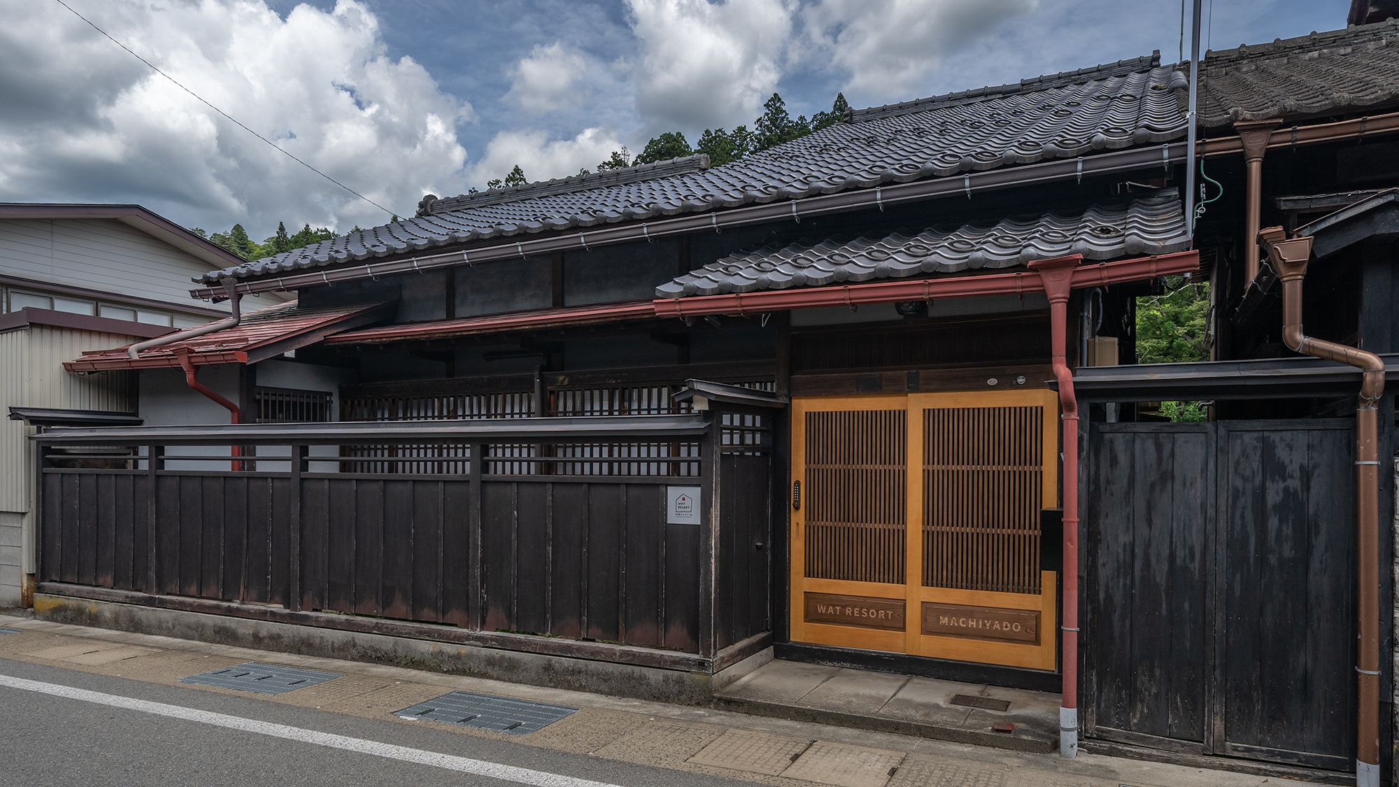 A traditional Japanese building with a wooden gate, a tiled roof, and a sign indicating 'WATRESORT MACHIYADO'.