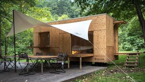 A wooden cabin with a deck, a table, and chairs. - Akaigawa Tomo Playpark Jubako (Akaigawa)