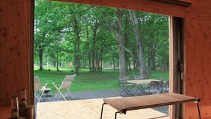 A room with a large window overlooking a grassy outdoor area with chairs and tables. - Akaigawa Tomo Playpark Jubako (Akaigawa)