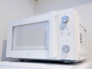 A white microwave with two dials and a control panel with instructions. - Vicoletto Inn Hakata Sumiyoshi (Fukuoka)